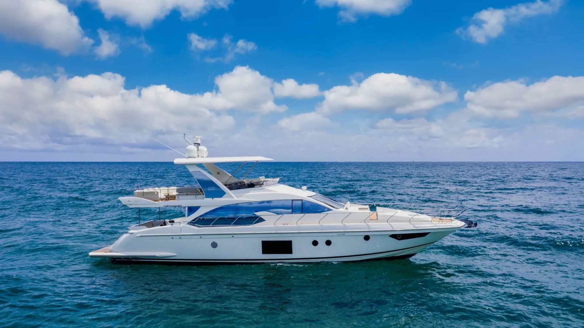 A white luxury yacht on a calm blue sea under a partly cloudy sky.