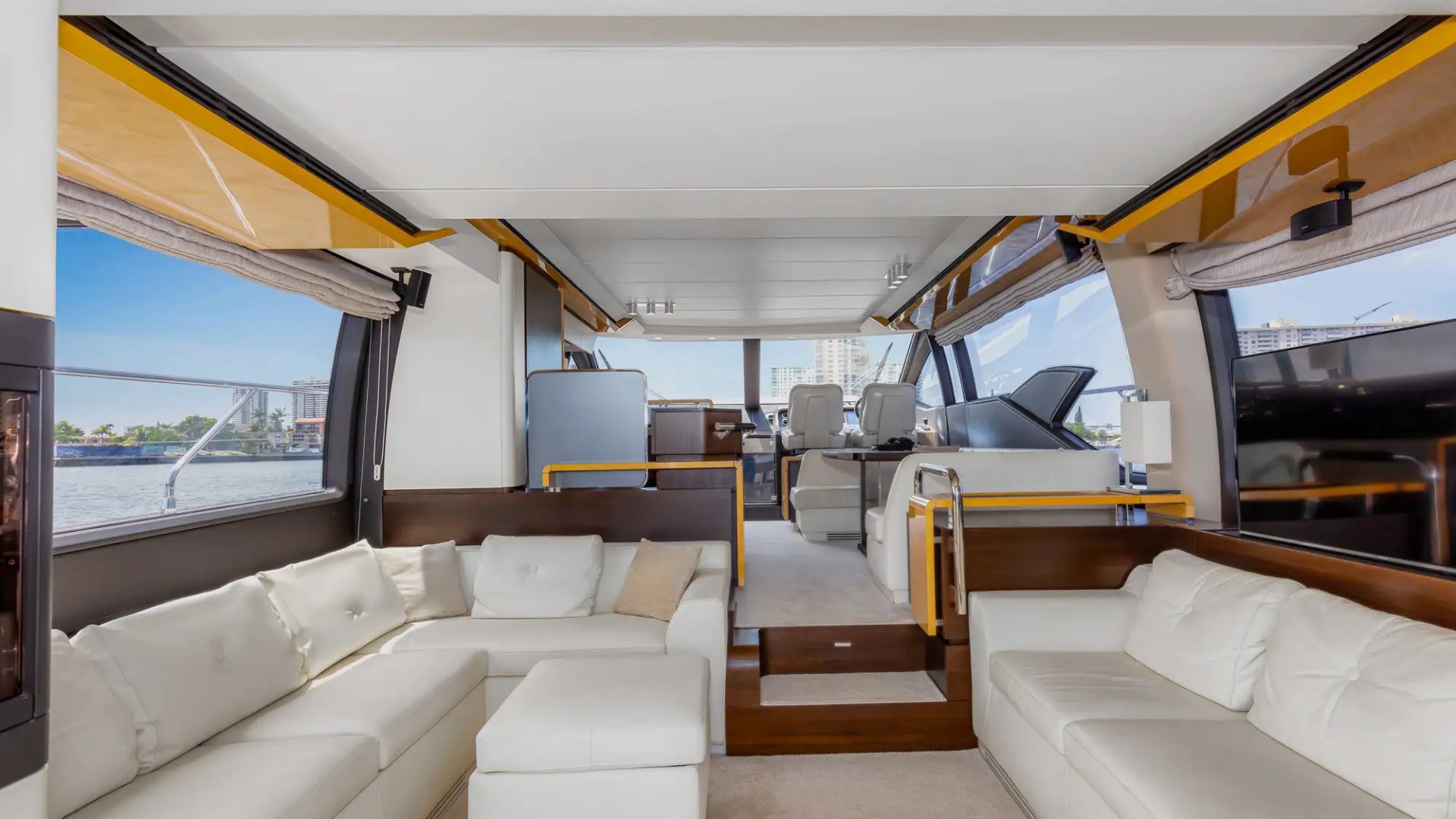 Modern yacht interior with white sofas and large windows.