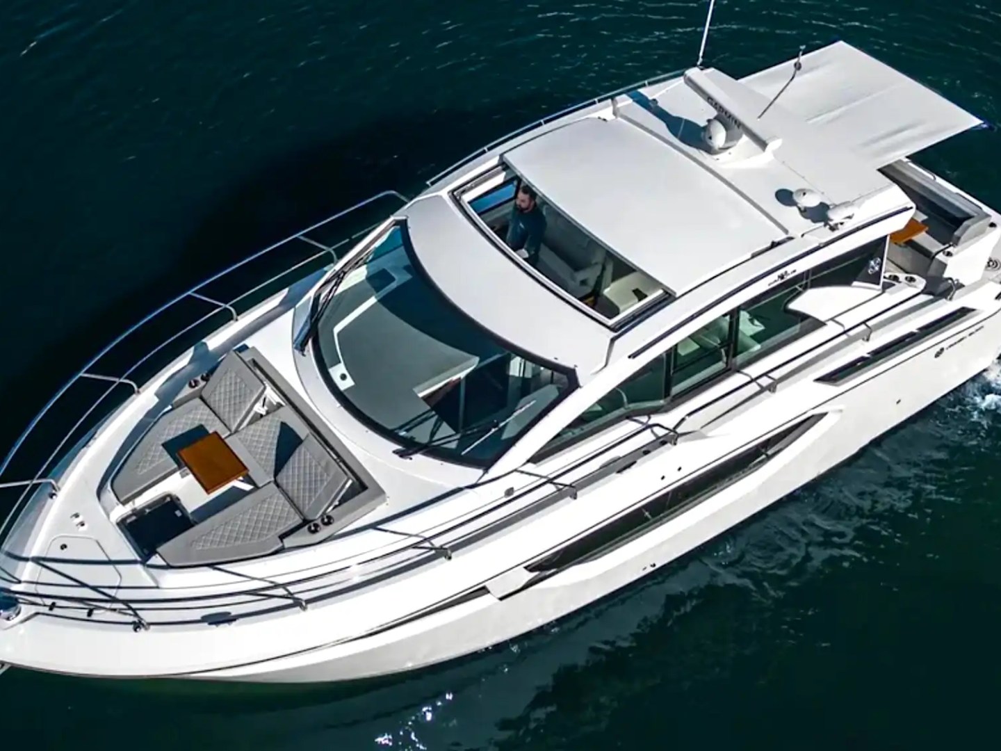 White motor yacht on dark blue water, viewed from above.