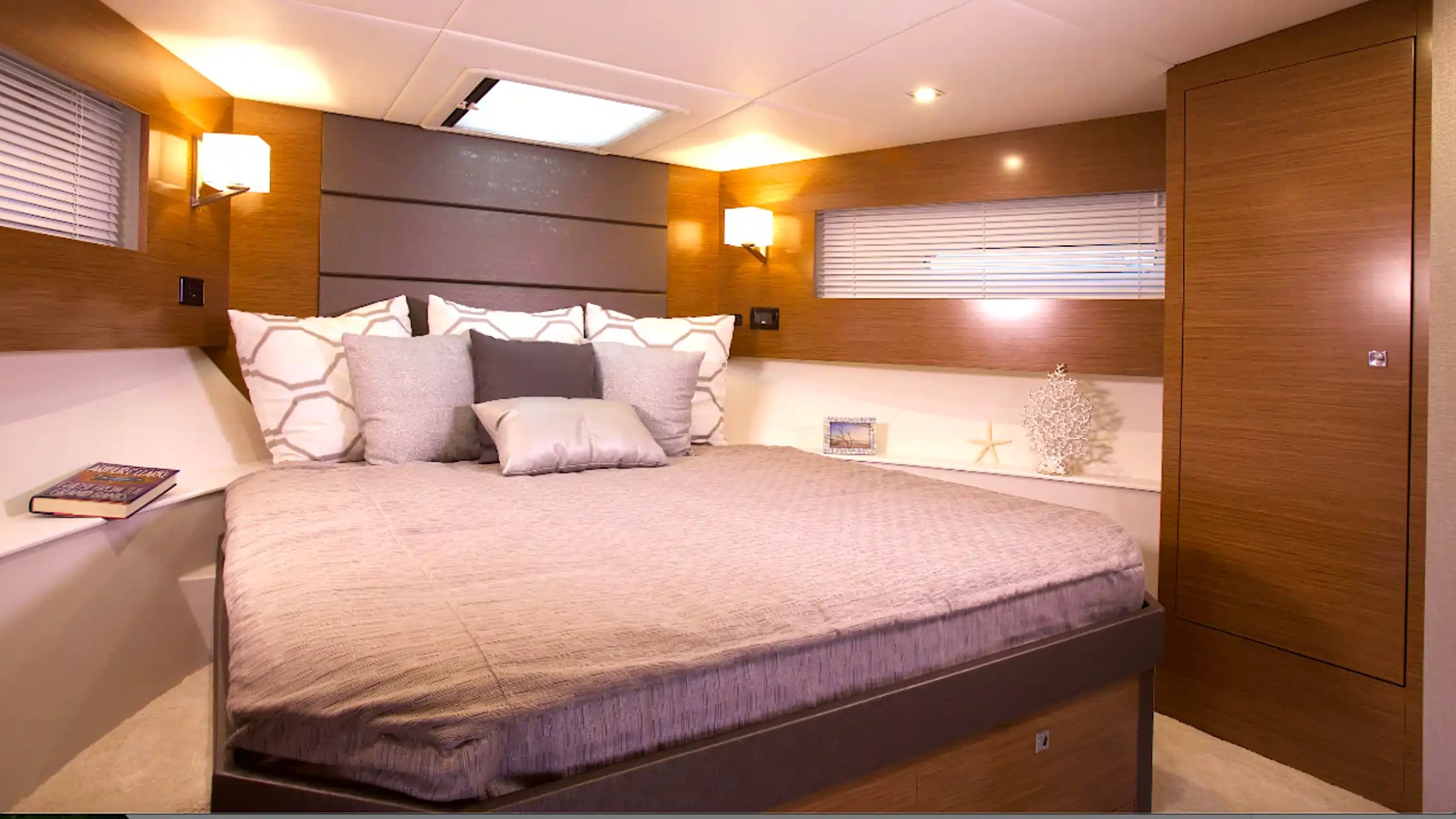 Cozy boat bedroom with a double bed, pillows, wooden walls, and soft lighting.