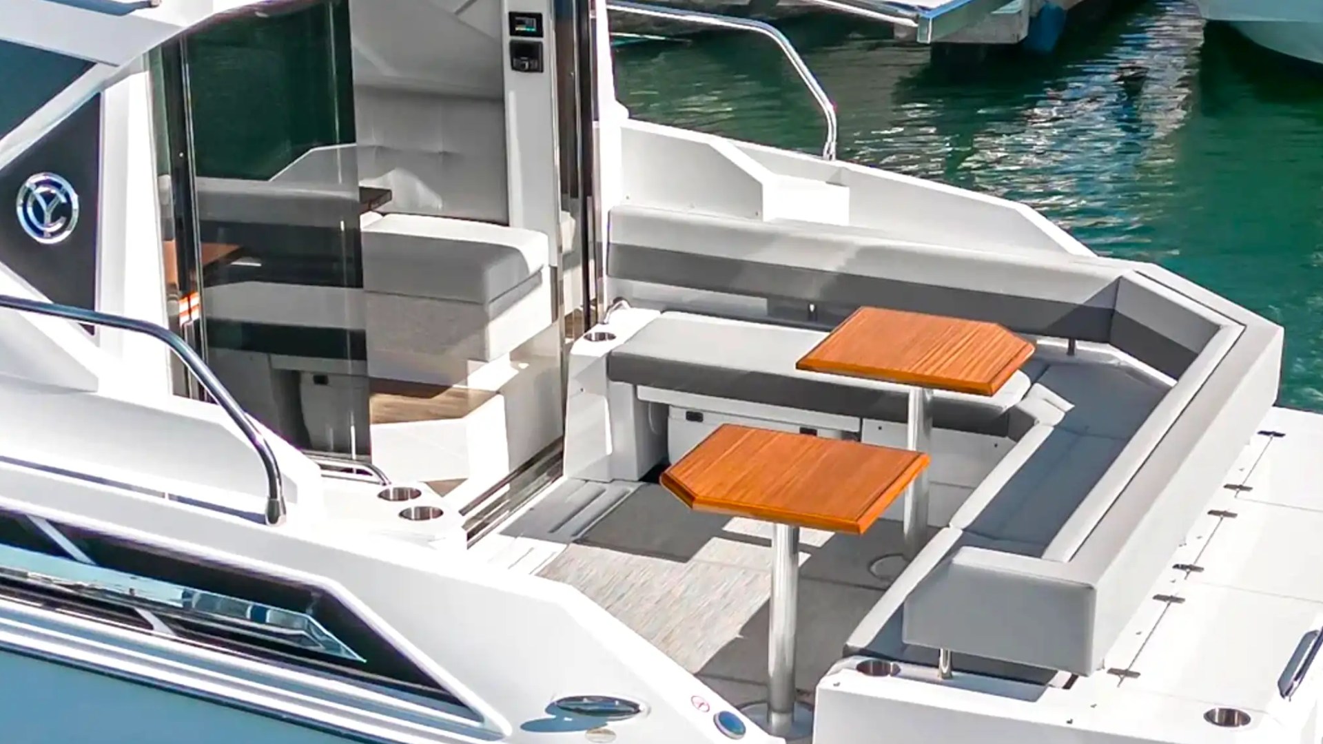 White yacht with outdoor seating and two wooden tables on the deck.