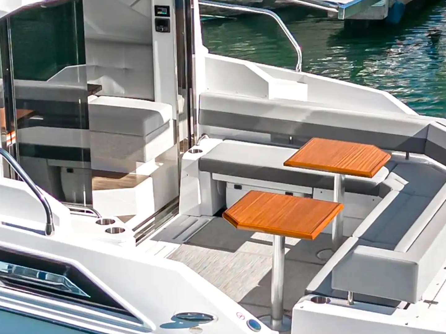 White yacht with outdoor seating and two wooden tables on the deck.