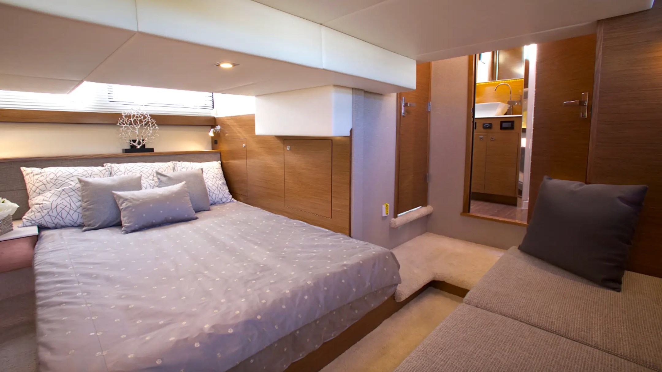 Modern bedroom with a bed, pillows, sofa, and wooden accents.