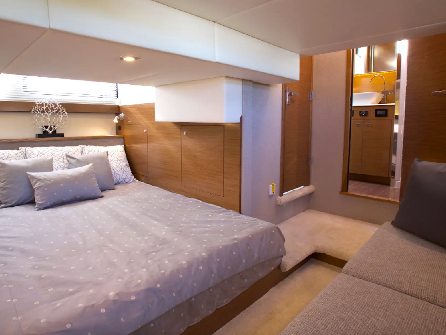 Modern bedroom with a bed, pillows, sofa, and wooden accents.