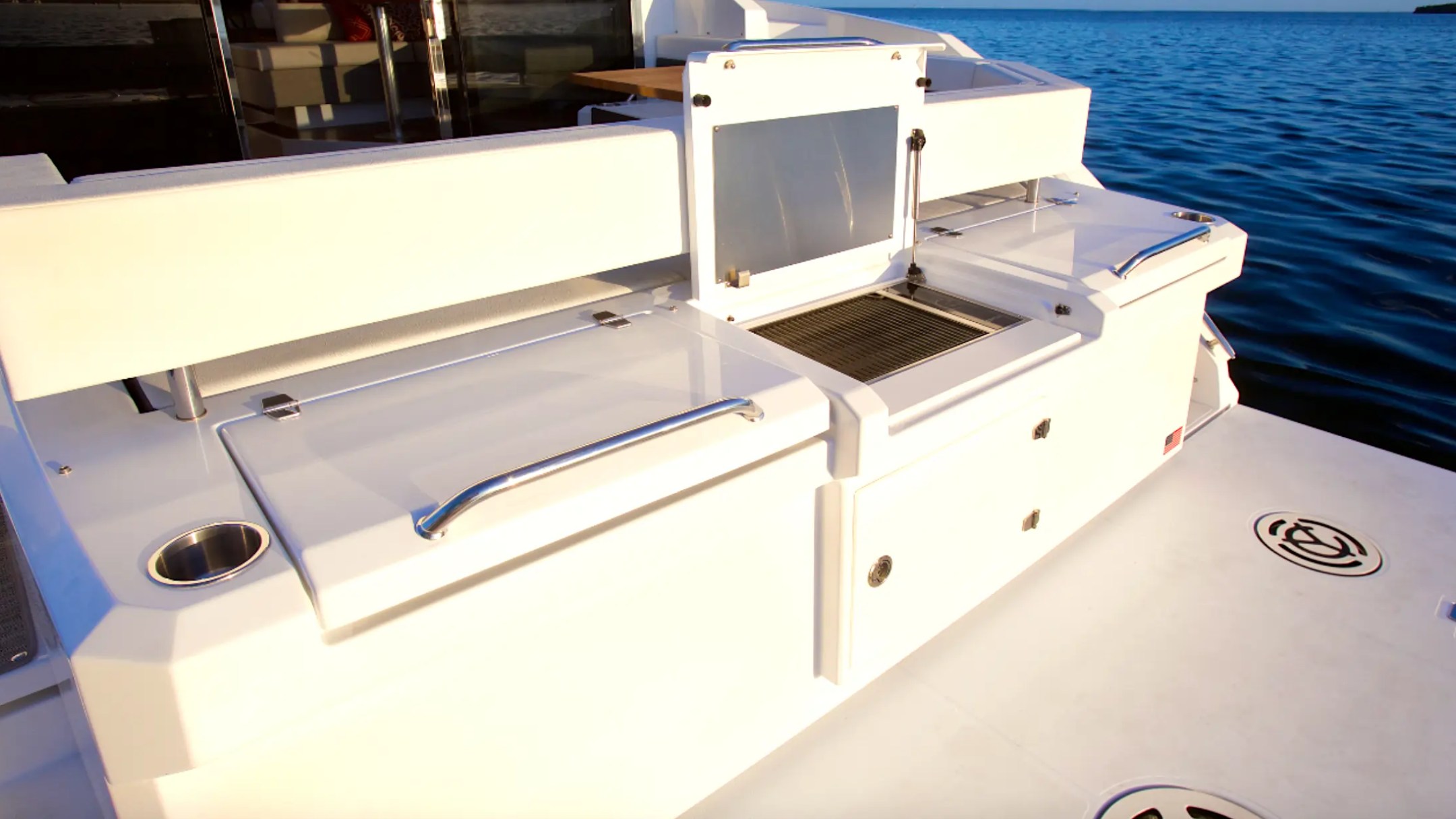 Boat deck with storage compartments and grill by the ocean.