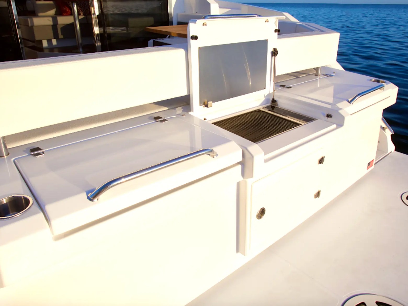 Boat deck with storage compartments and grill by the ocean.
