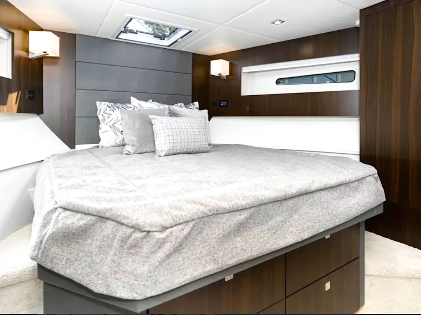 Interior of a bedroom with a gray bed, wood paneling, and wall lamps.