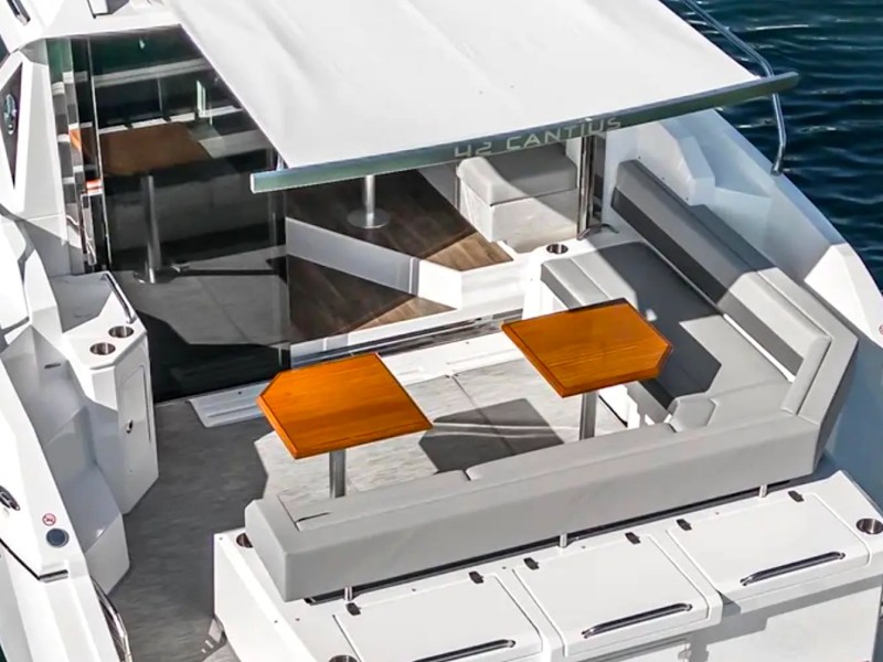 Luxury yacht with open deck seating and tables on water.