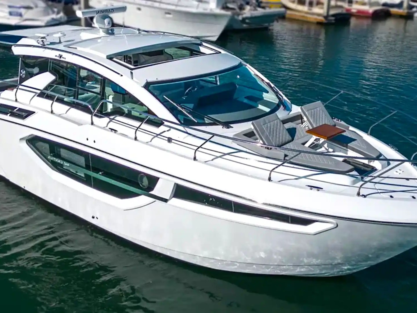Luxury white yacht docked in a marina with several other boats.