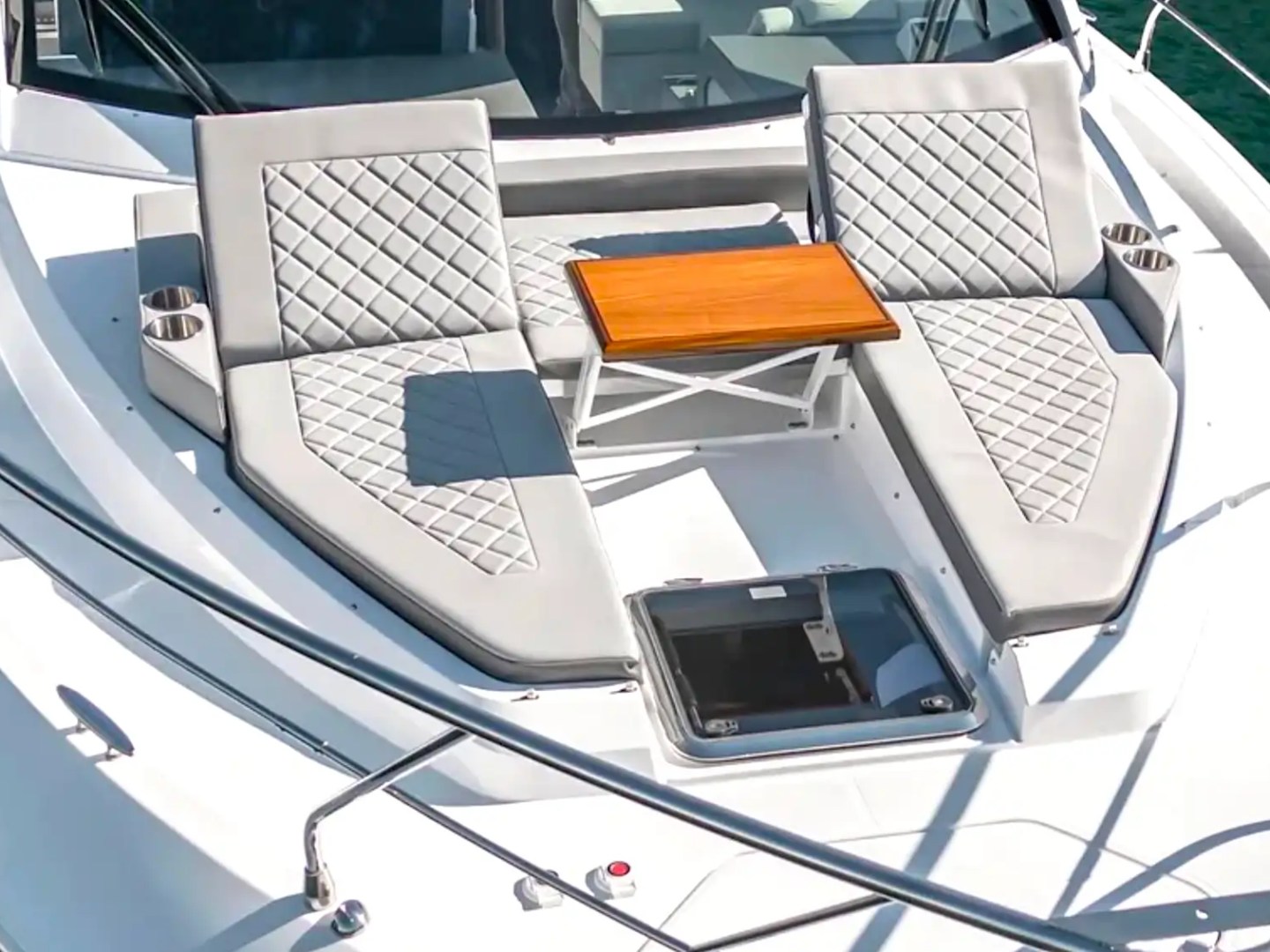 Sun deck of a yacht with two cushioned lounge chairs and a small wooden table.