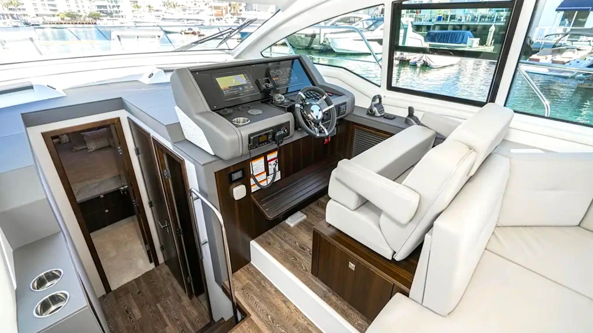 Interior view of a yacht's cockpit with steering wheel and navigation equipment.