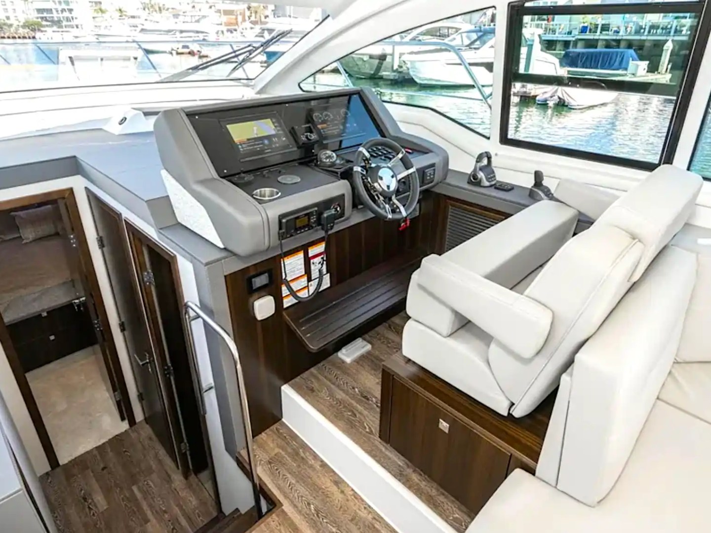 Interior view of a yacht's cockpit with steering wheel and navigation equipment.