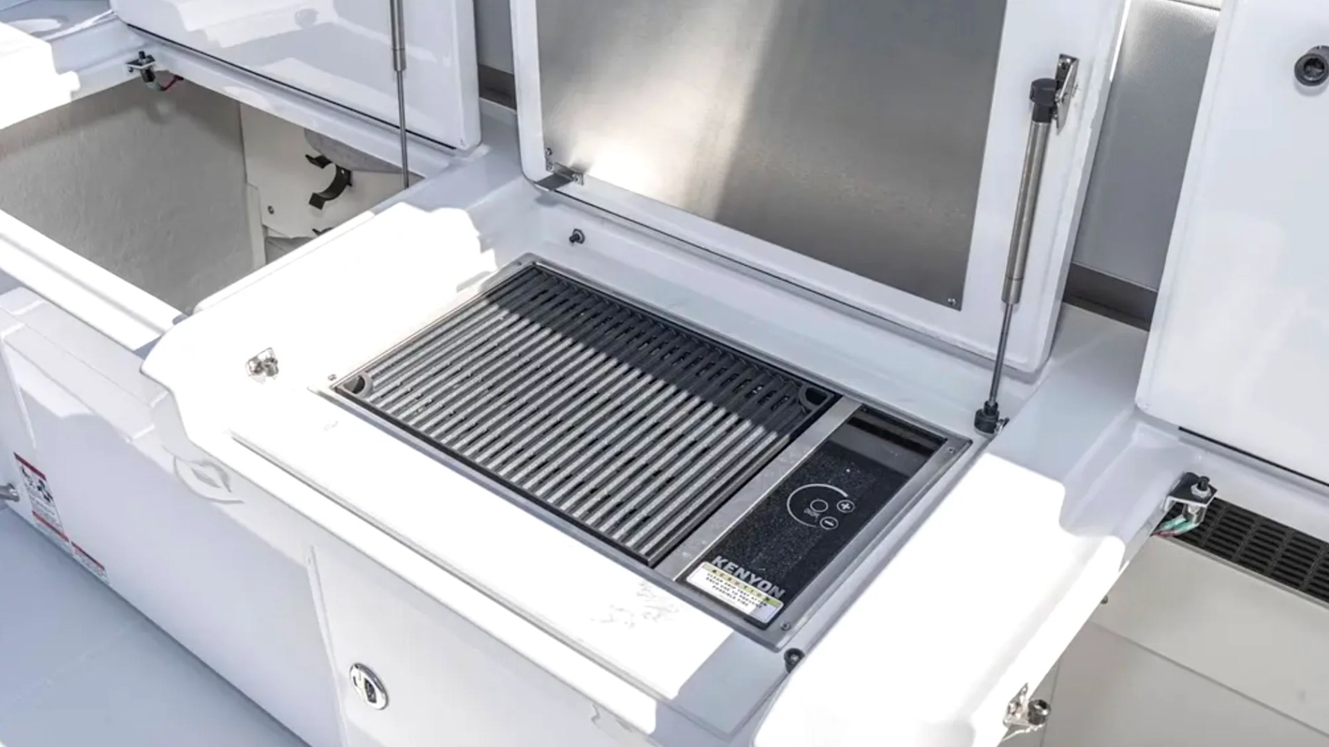 Outdoor grill on a boat deck with lids open, displaying a cooking surface.