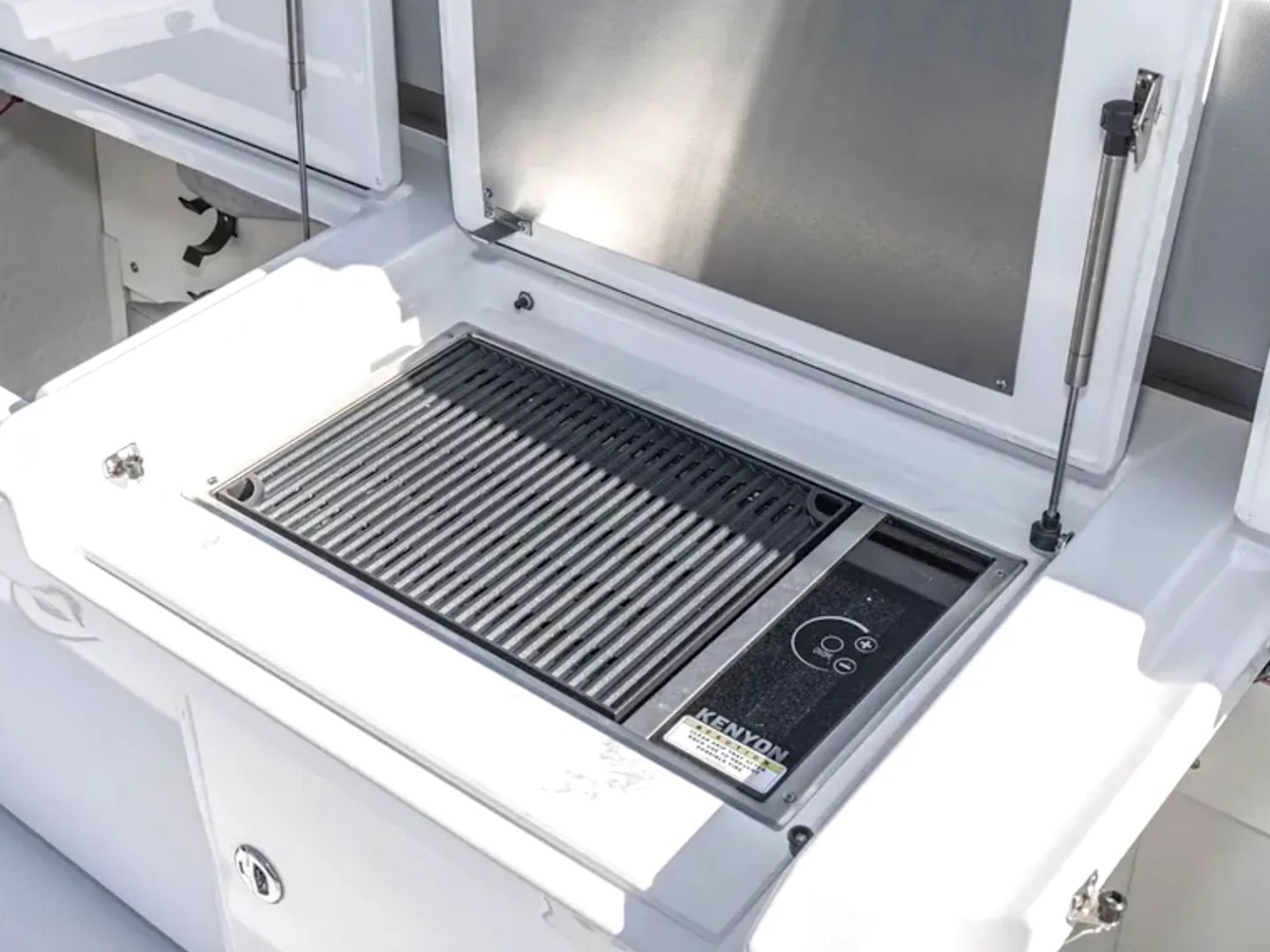 Outdoor grill on a boat deck with lids open, displaying a cooking surface.
