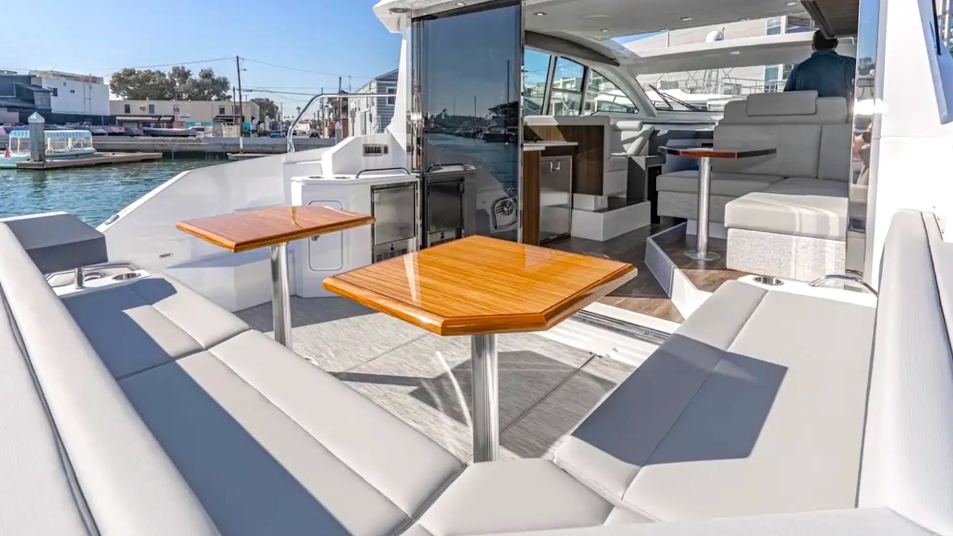 Luxury yacht deck with seating, tables, and open sliding glass door.
