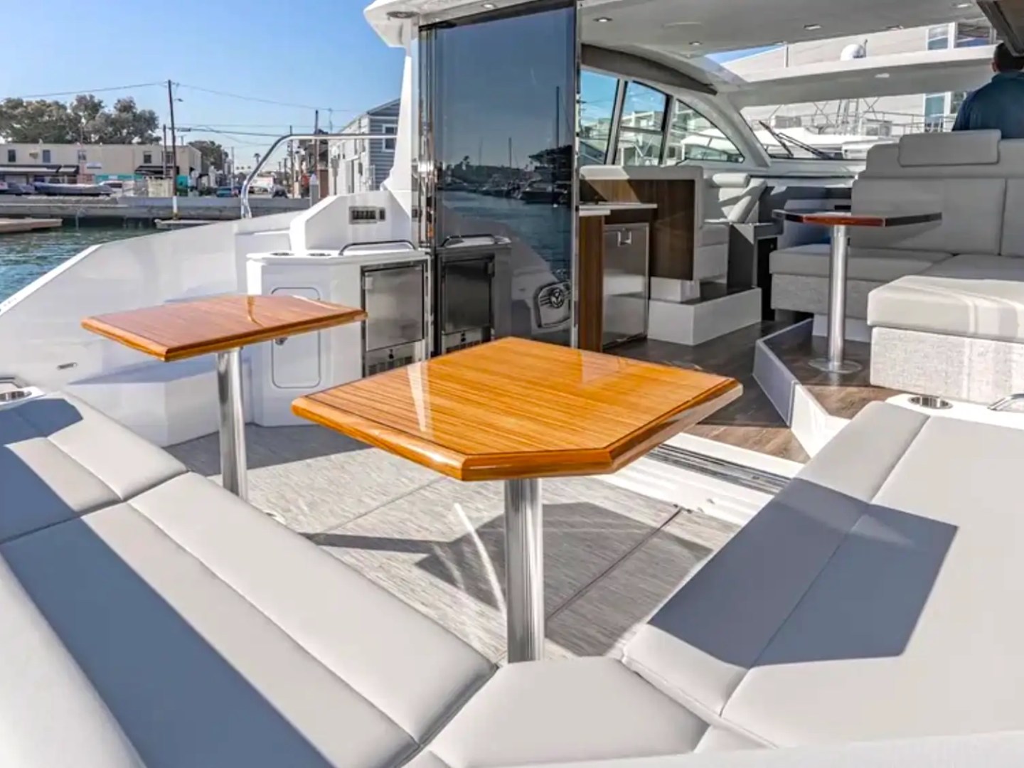 Luxury yacht deck with seating, tables, and open sliding glass door.
