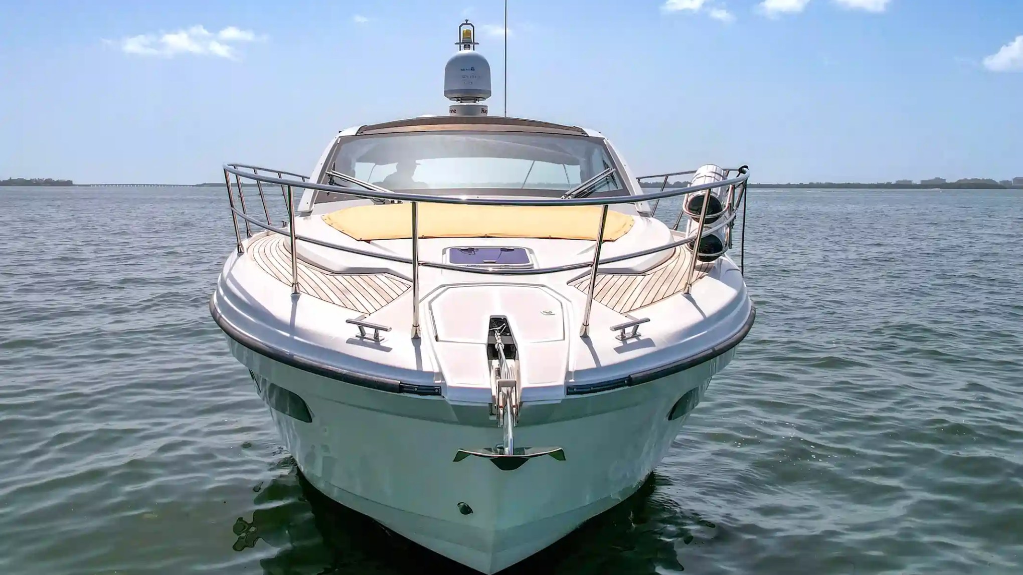 Front view of a luxury yacht on calm water under clear skies.