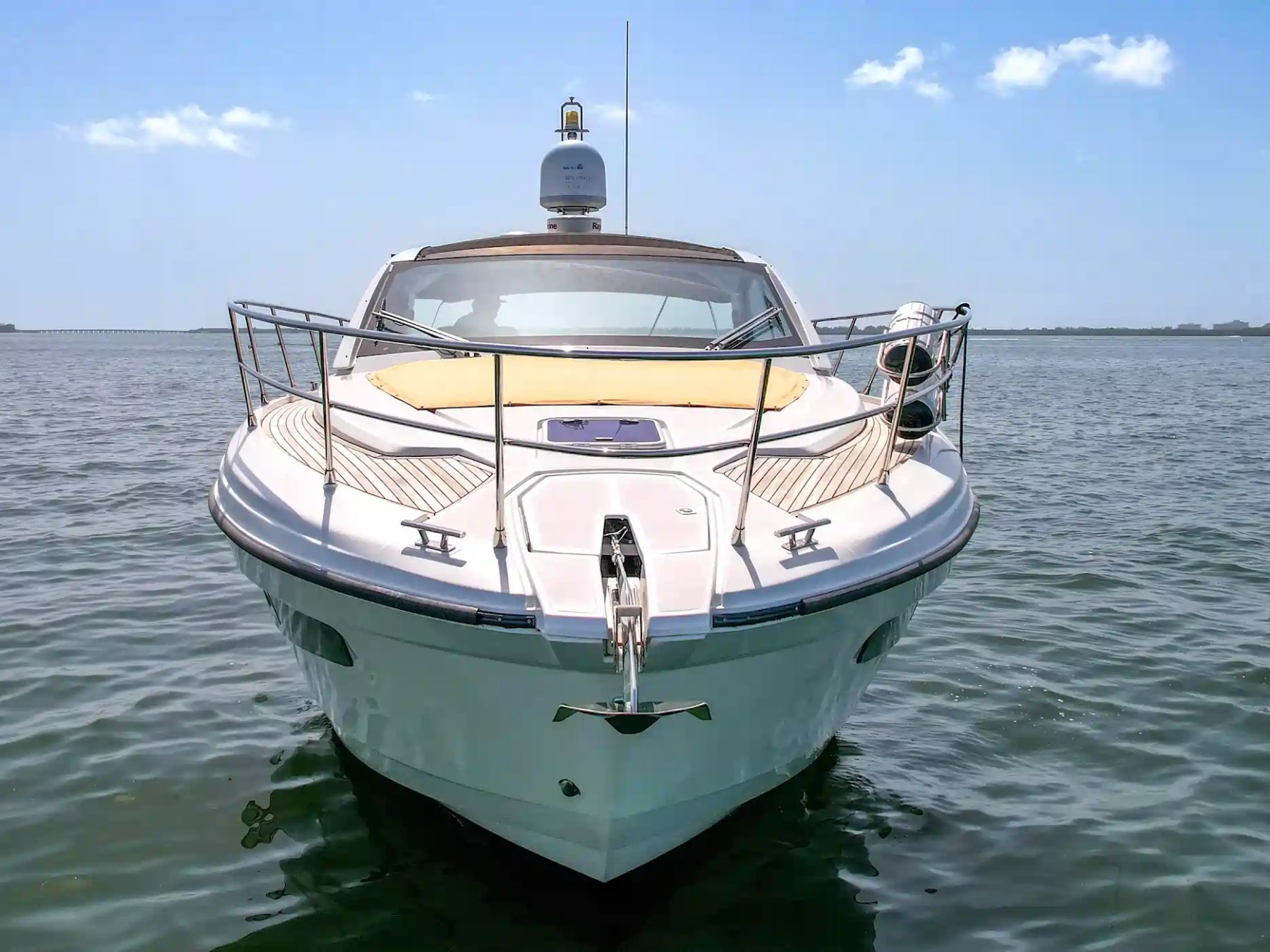 Front view of a luxury yacht on calm water under clear skies.