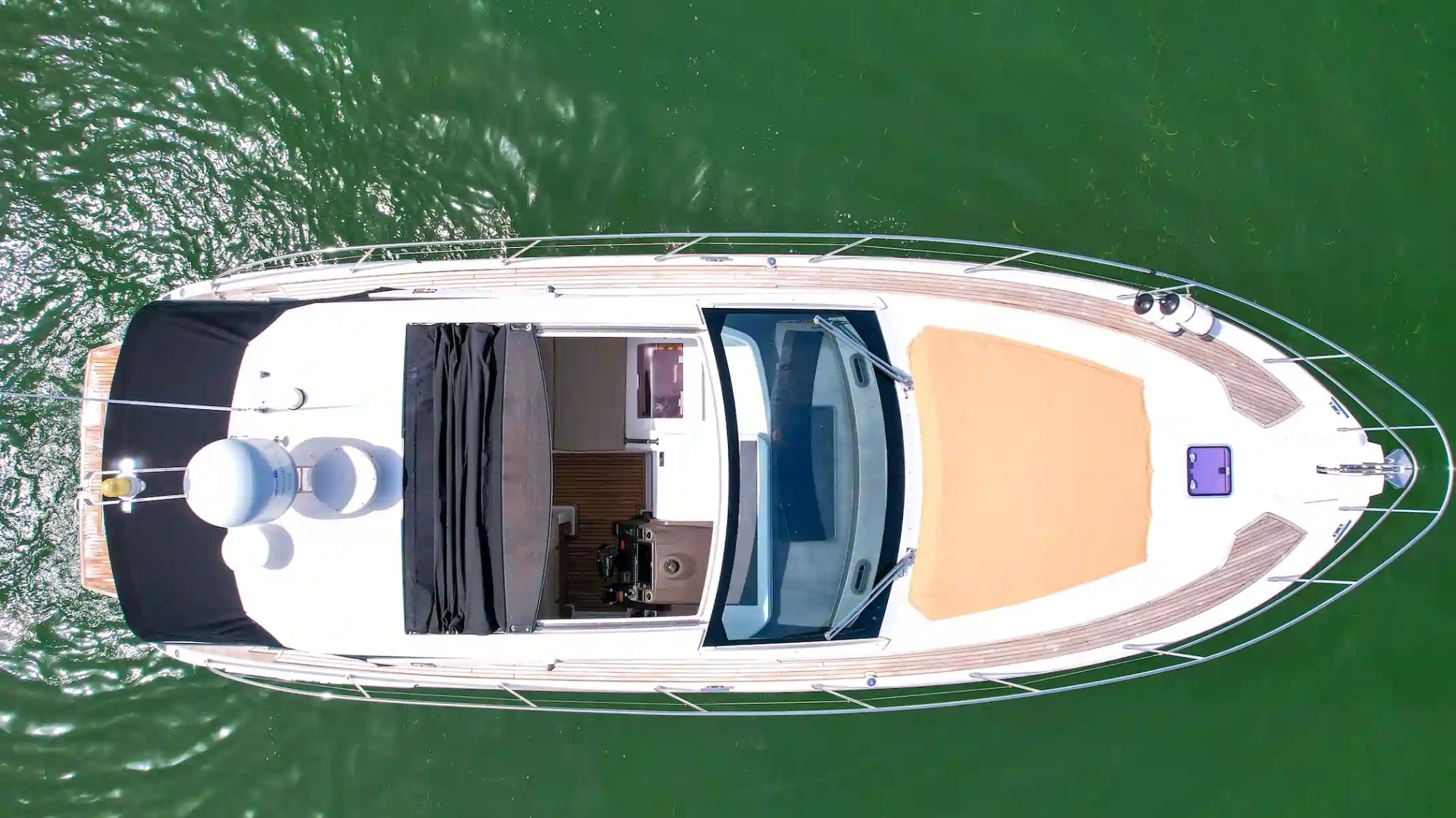 Bird's-eye view of a yacht on green water.