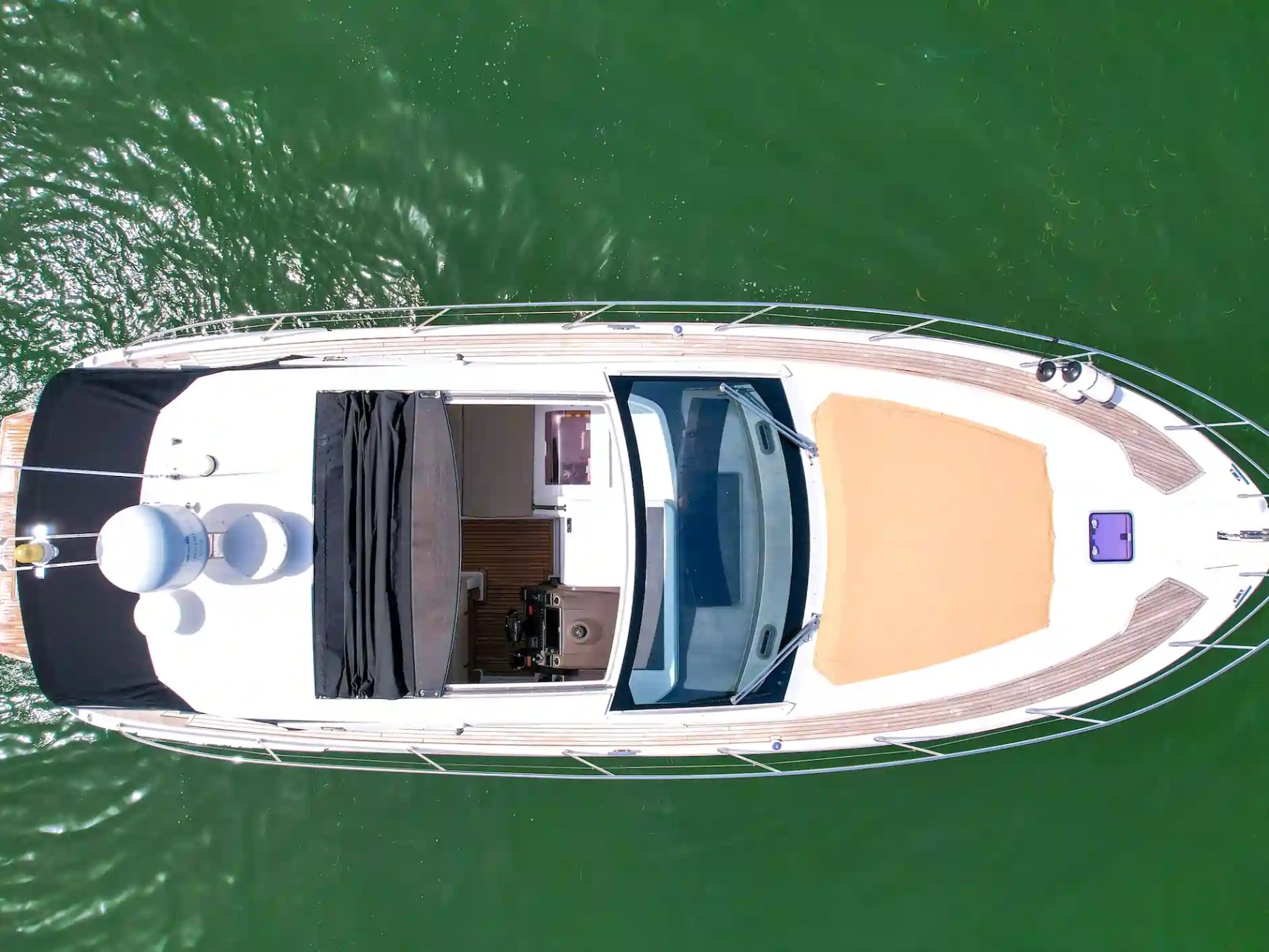 Bird's-eye view of a yacht on green water.
