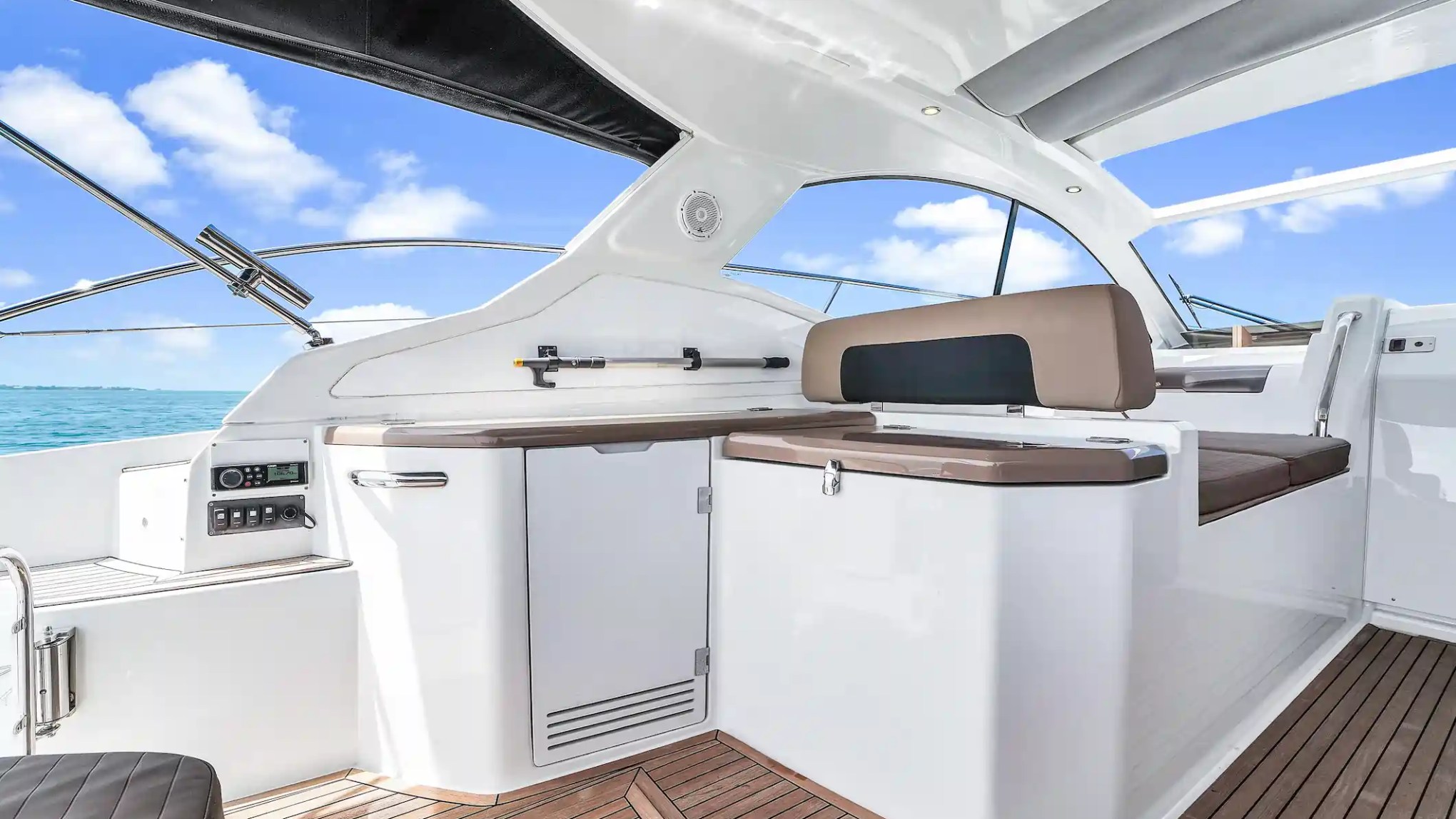 Luxury boat interior with wooden floor, white furnishings, and a view of the ocean.