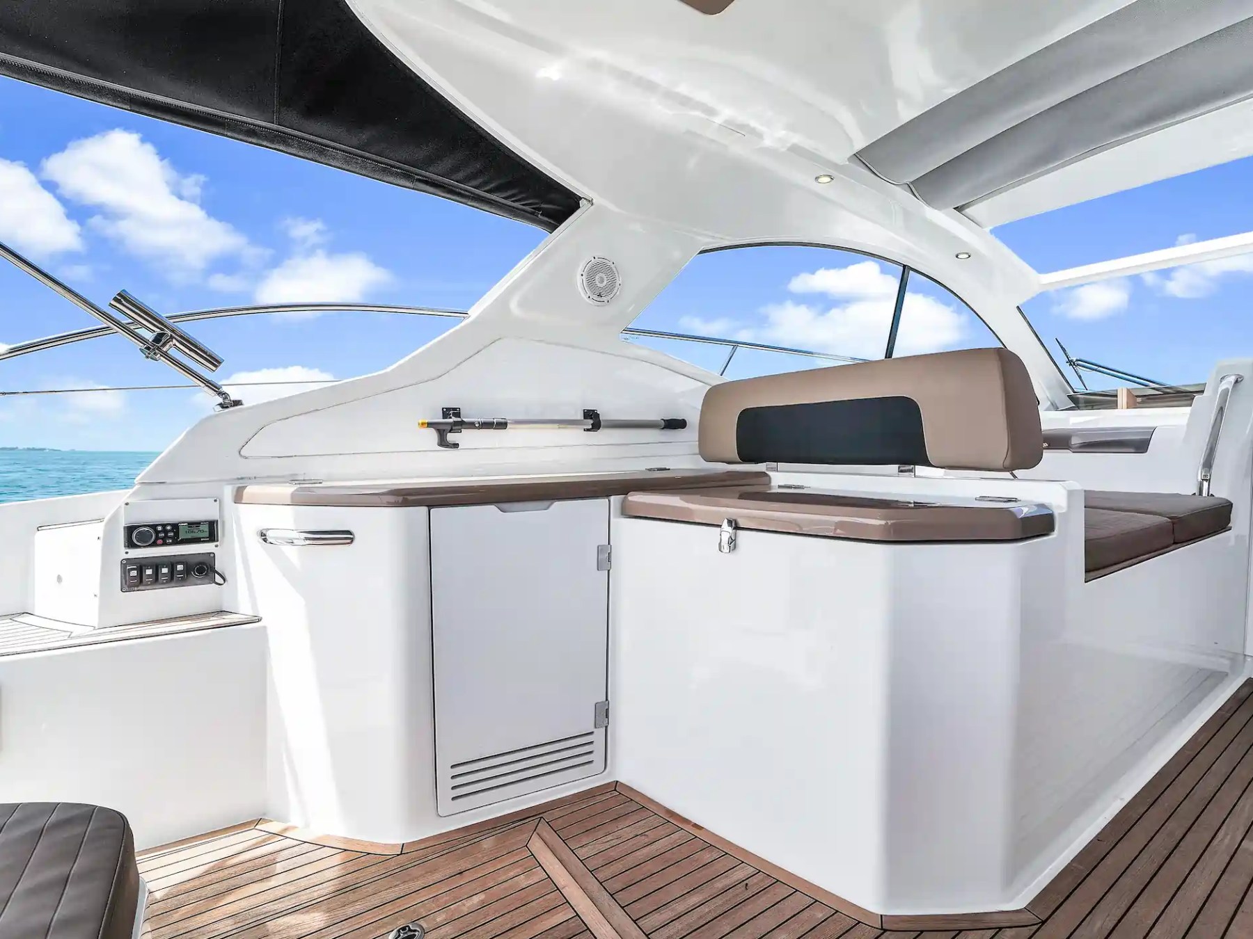 Luxury boat interior with wooden floor, white furnishings, and a view of the ocean.