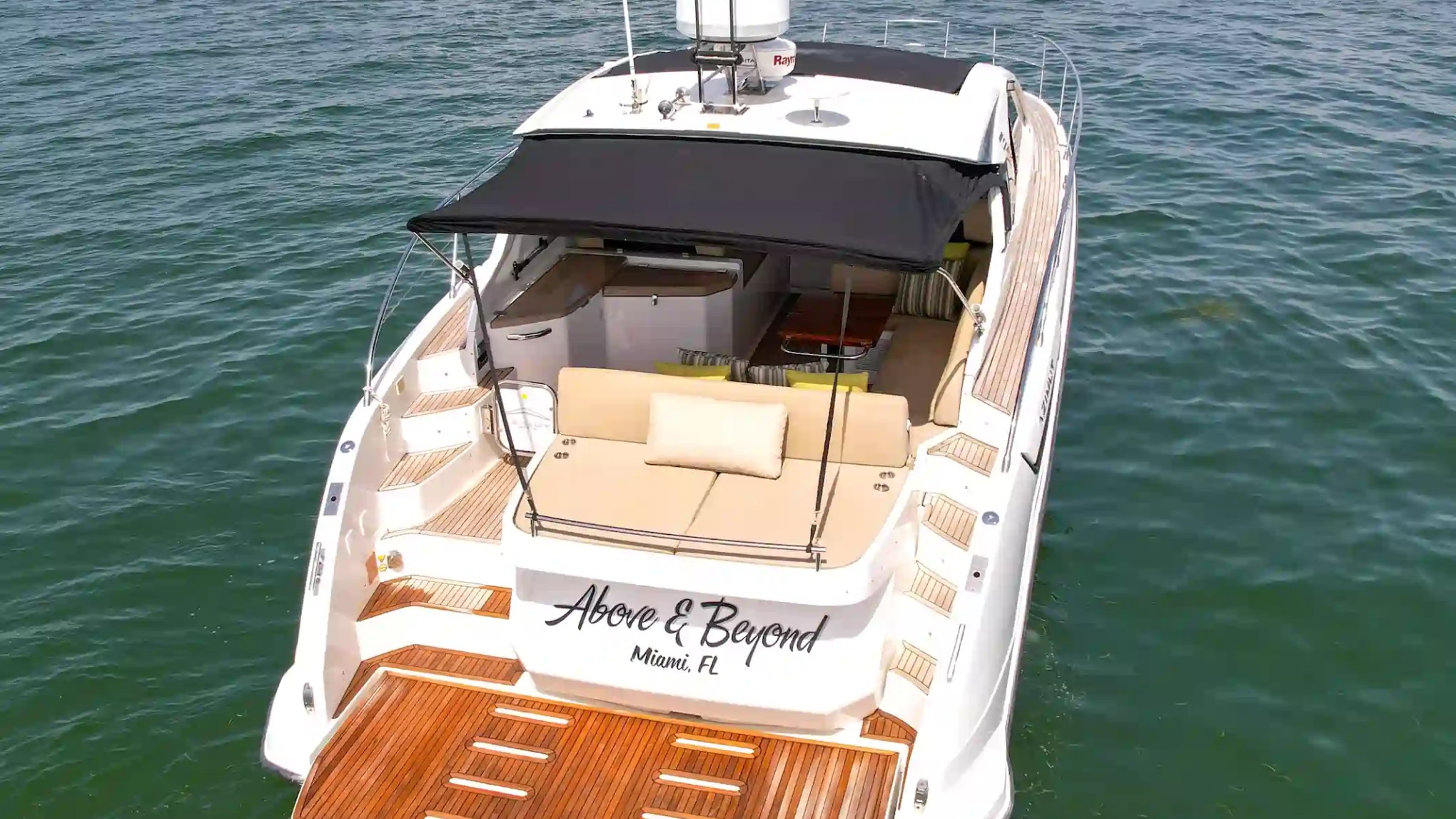 Luxury yacht named 'Above and Beyond' on the water, viewed from the rear.