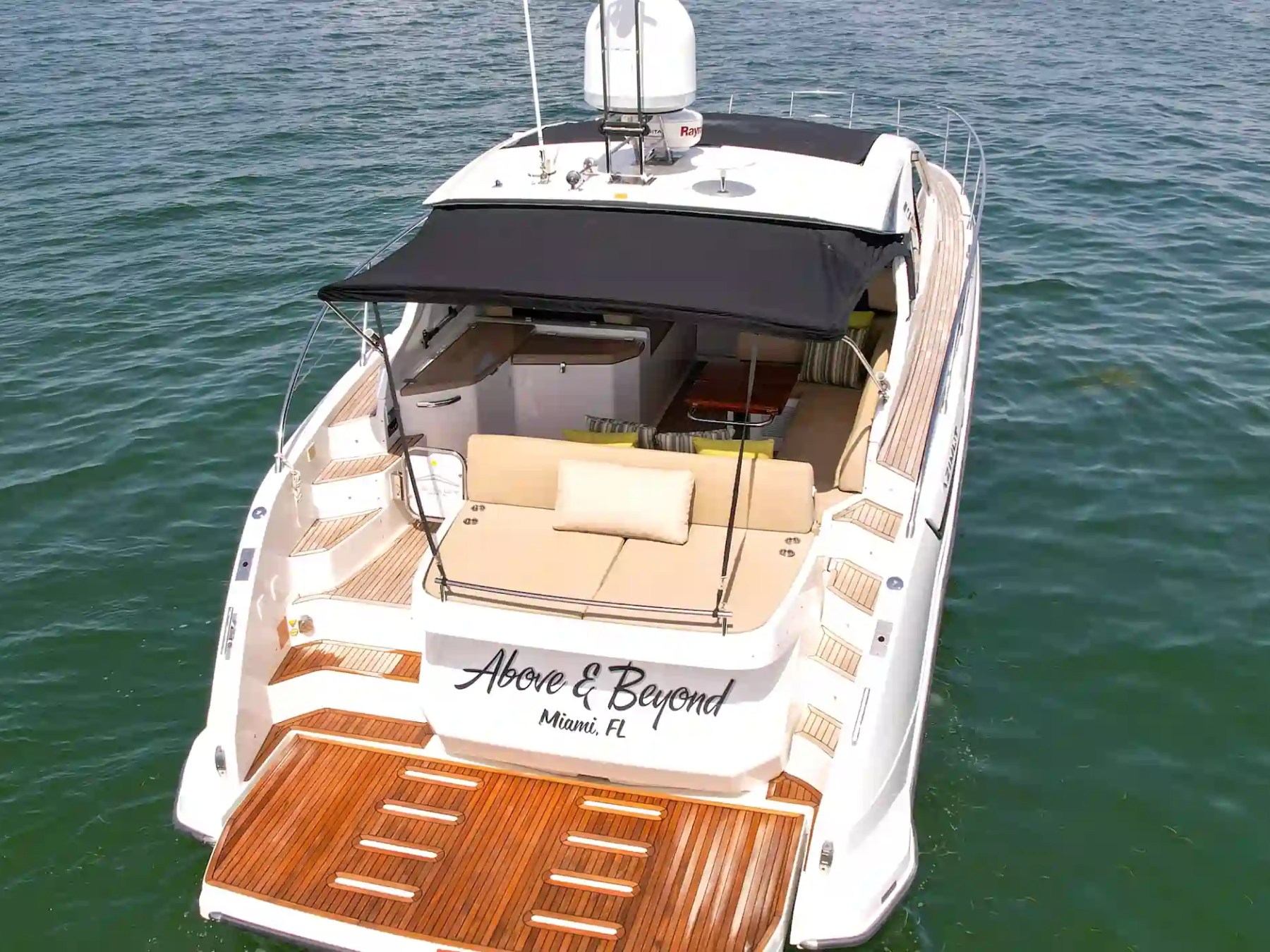 Luxury yacht named 'Above and Beyond' on the water, viewed from the rear.