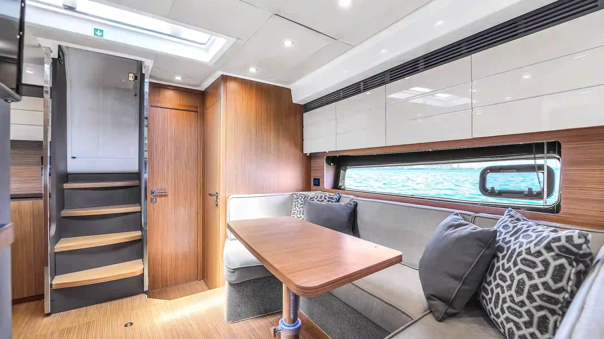 Modern boat interior with wood paneling, seating area, and stairs.