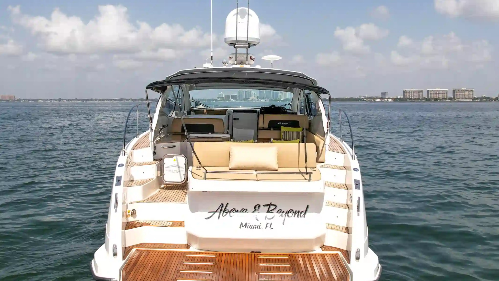 Rear view of a yacht on the water under a partly cloudy sky.