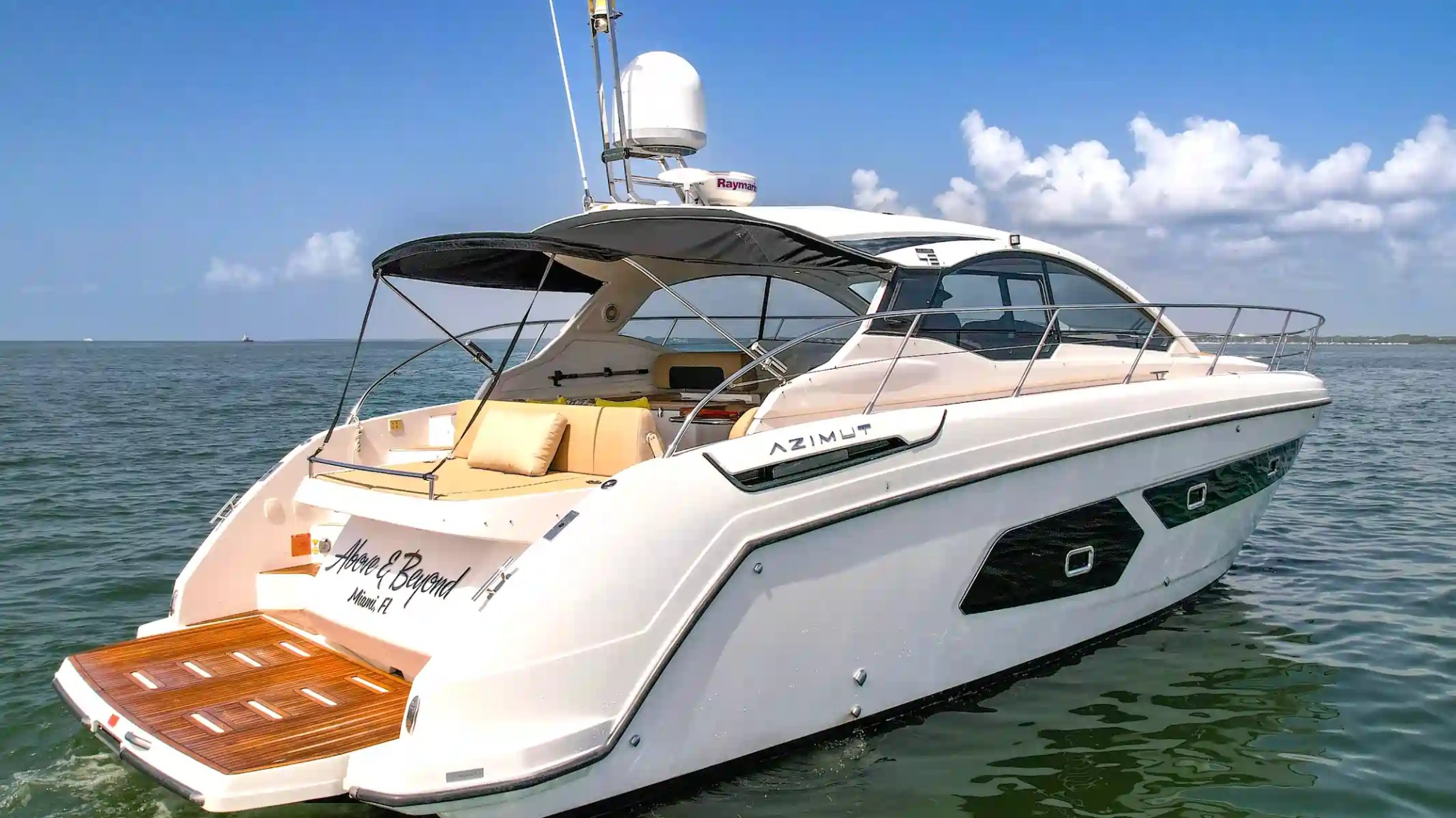A luxury motor yacht cruising on calm sea under a clear blue sky.