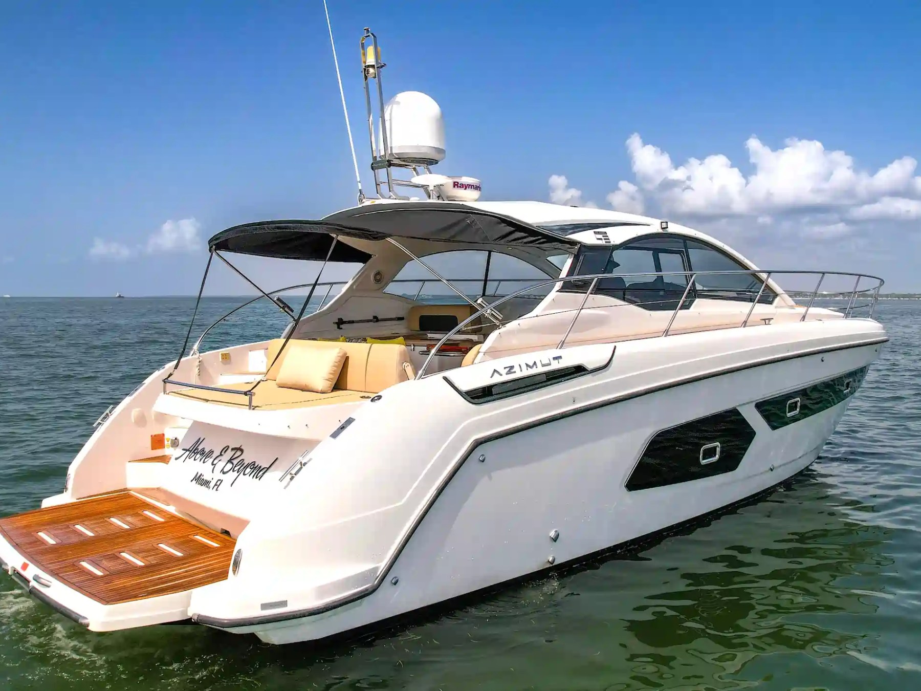 A luxury motor yacht cruising on calm sea under a clear blue sky.