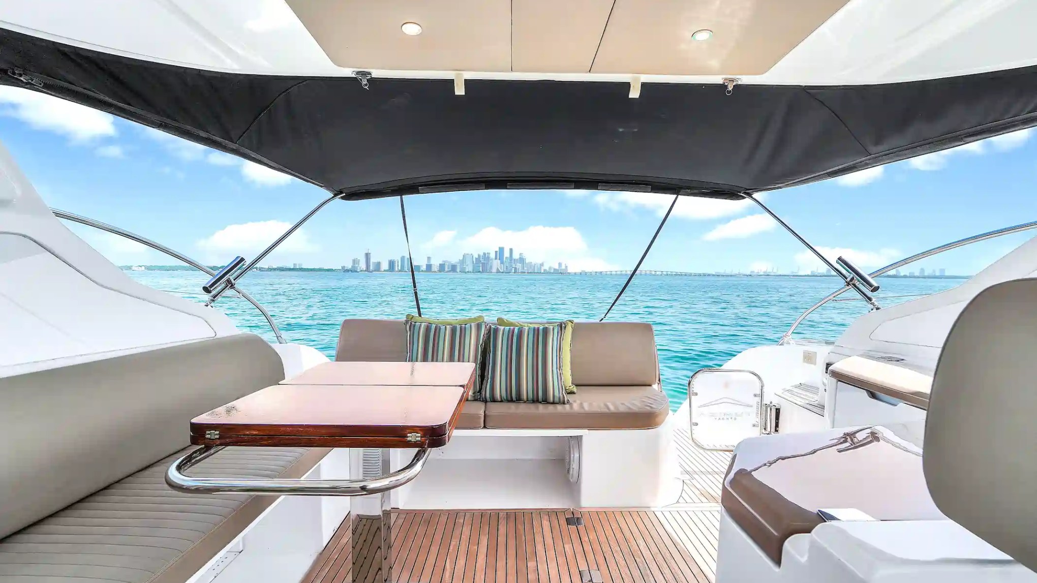 View from yacht deck with seating, table, and city skyline in background.