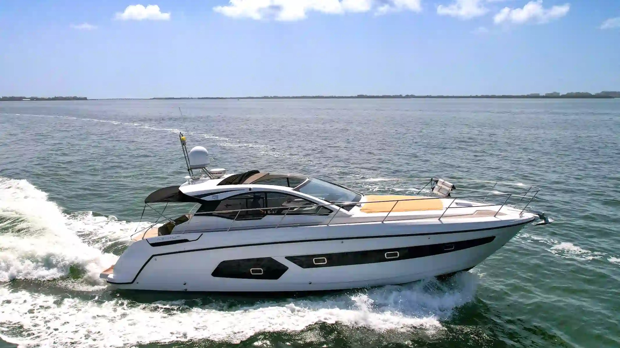 Luxury motor yacht cruising on calm ocean water under a clear blue sky.