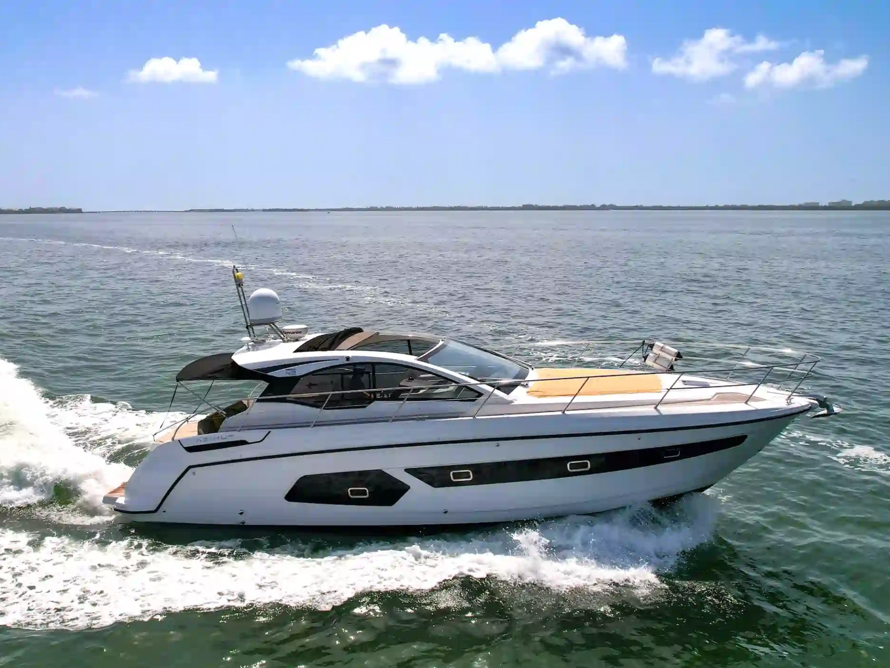Luxury motor yacht cruising on calm ocean water under a clear blue sky.