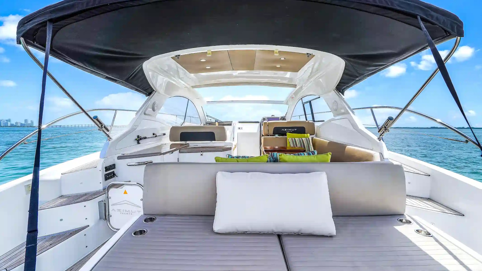 Modern yacht interior with seating and roof canopy, ocean view.