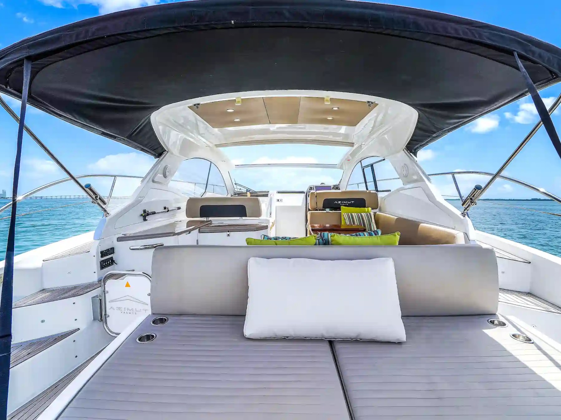 Modern yacht interior with seating and roof canopy, ocean view.