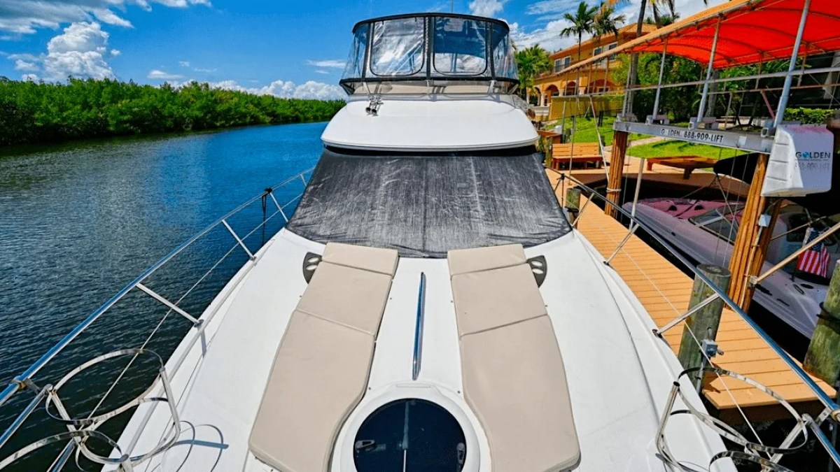 This 44 foot Meridian Boat Rental features dual bow sun pads on the foredeck while docked along Cape Coral waterways with waterfront homes and mangrove-lined shores in view.