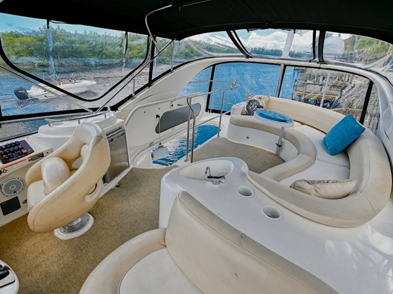 This 44 foot Meridian Boat Rental features an elevated flybridge lounge with wraparound seating, helm station, beverage counter, and waterfront views while docked in Cape Coral, Florida.