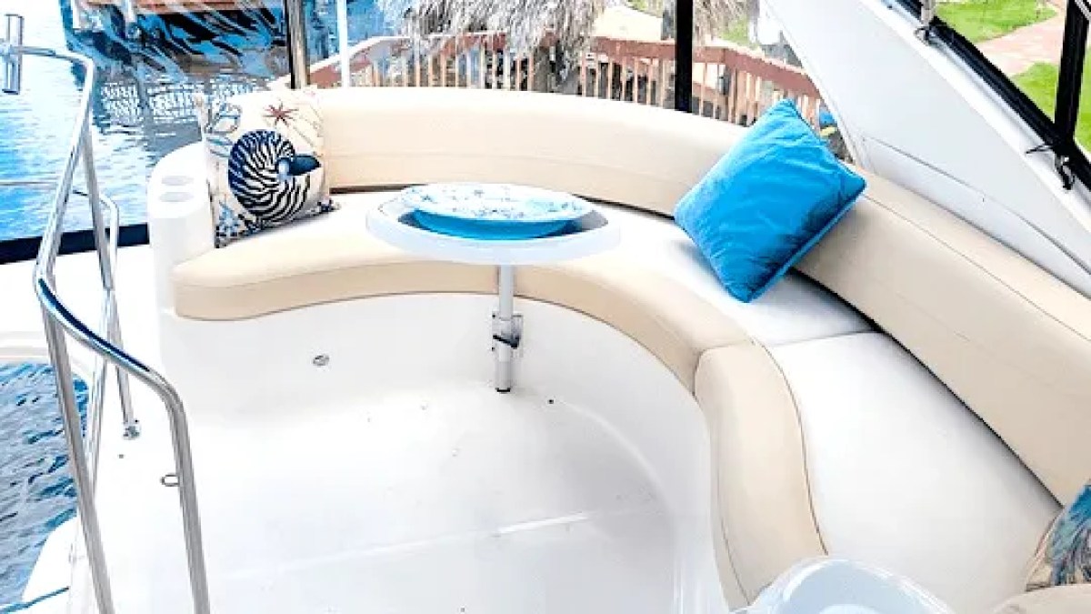 This 44 foot Meridian Boat Rental features curved flybridge lounge seating with a table, decorative cushions, and open-air relaxation space while docked in Cape Coral, Florida.