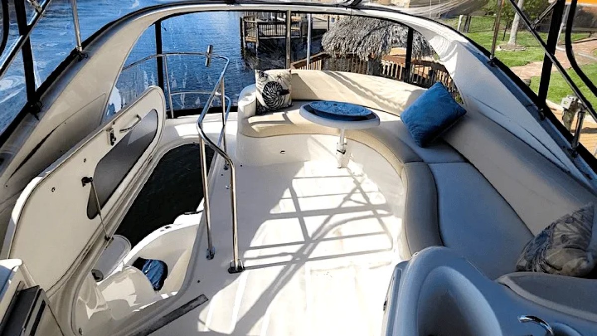 This 44 foot Meridian Boat Rental features an open flybridge lounge with curved wraparound seating, a cocktail table, and waterfront views while docked in Cape Coral, Florida.