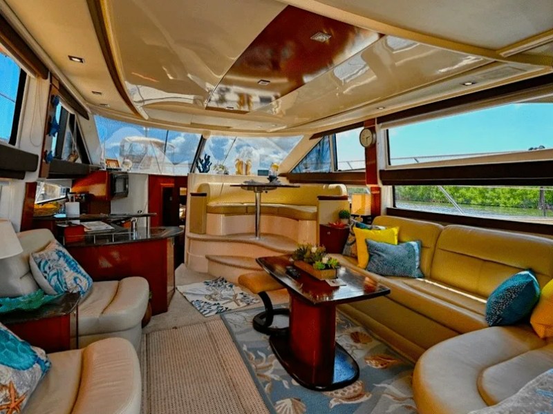 This 44 foot Meridian Boat Rental features a spacious salon with wraparound seating, panoramic side windows, wood cabinetry, and a dining lounge area while docked in Cape Coral, Florida.