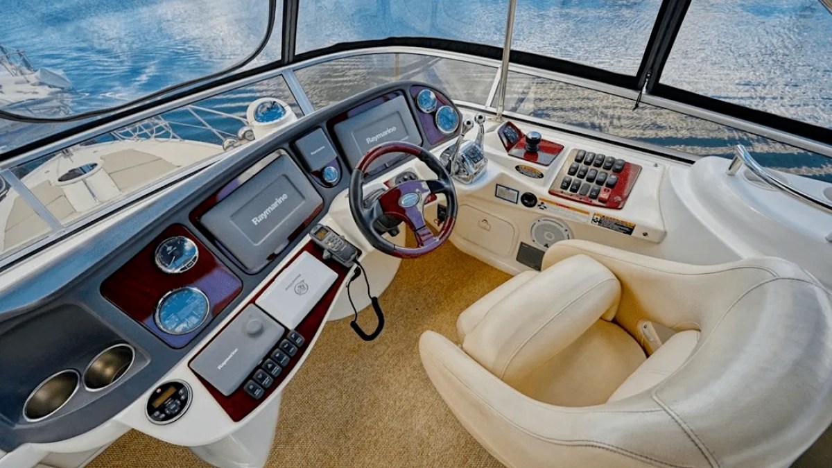 This 44 foot Meridian Boat Rental features an elevated flybridge helm with dual Raymarine displays, captain’s chair, navigation controls, and panoramic water views in Cape Coral, Florida.