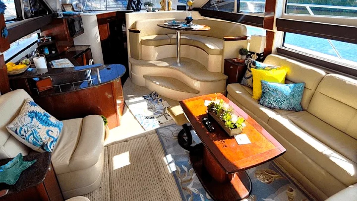 This 44 foot Meridian Boat Rental features a spacious salon with wraparound seating, large panoramic windows, wood finishes, and a dining area while cruising in Cape Coral, Florida.