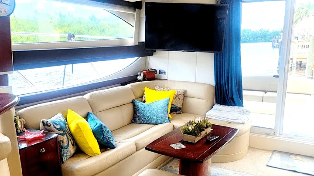 This 44 foot Meridian Boat Rental features a comfortable salon lounge with wraparound seating, accent pillows, a coffee table, television, and large waterfront windows in Cape Coral, Florida.