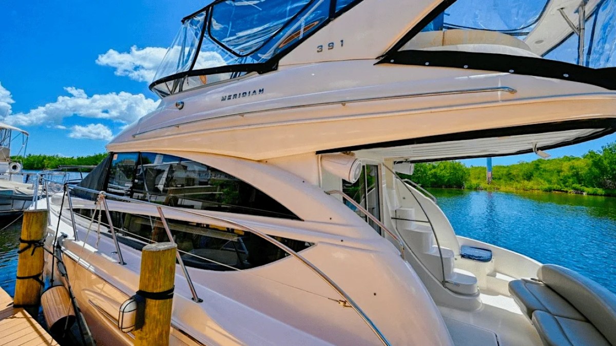This 44 foot Meridian Boat Rental is docked along Cape Coral waterways, showcasing its sleek flybridge profile, side deck access, tinted salon windows, and scenic Southwest Florida waterfront views.