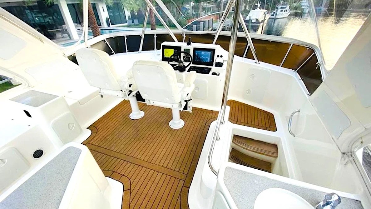 This 50 foot AfriCat Yacht Charter features a spacious flybridge helm with dual captain chairs, navigation electronics, teak-style decking, and panoramic waterfront views near Fort Myers and Sanibel Island.