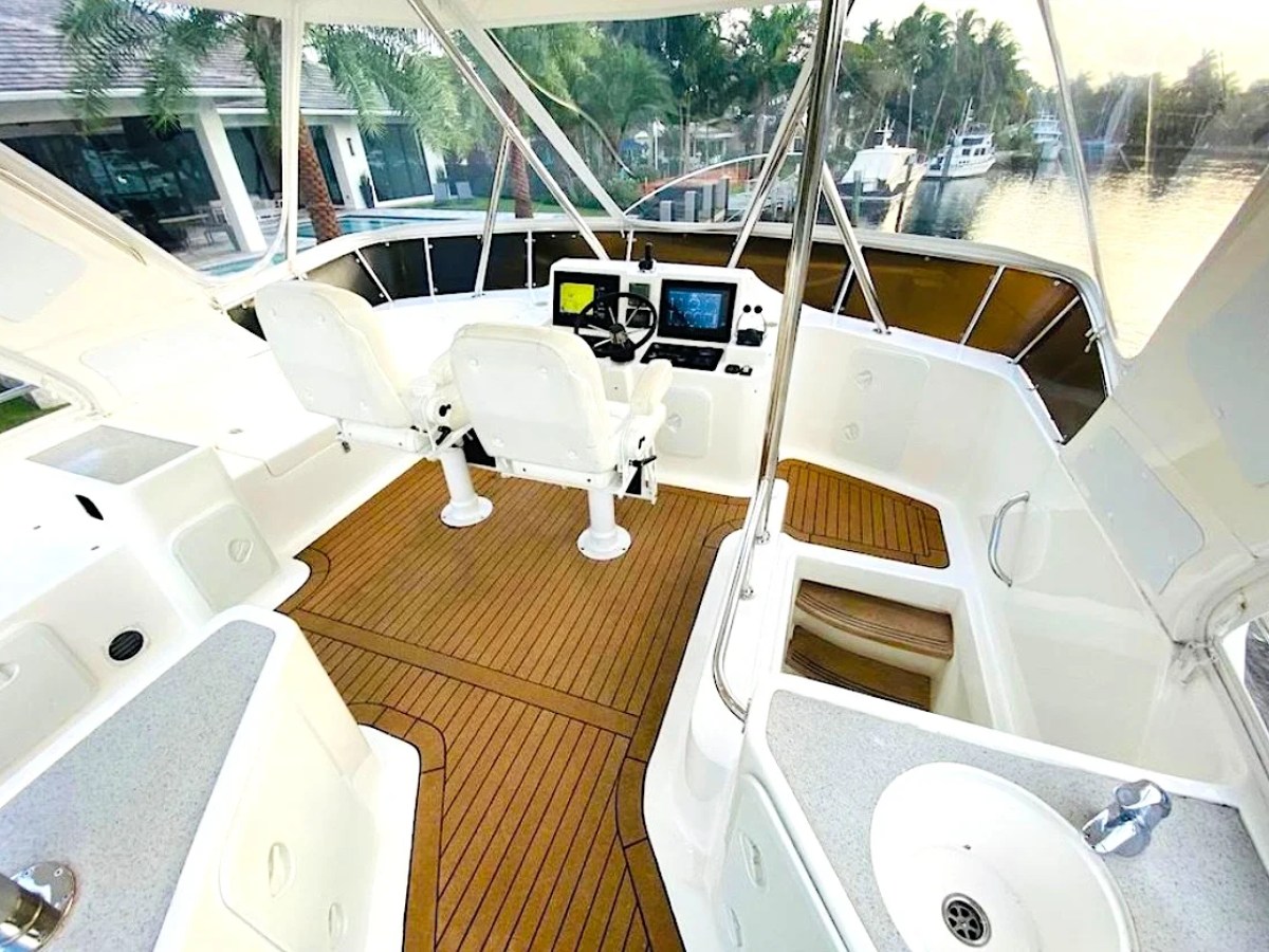 This 50 foot AfriCat Yacht Charter features a spacious flybridge helm with dual captain chairs, navigation electronics, teak-style decking, and panoramic waterfront views near Fort Myers and Sanibel Island.