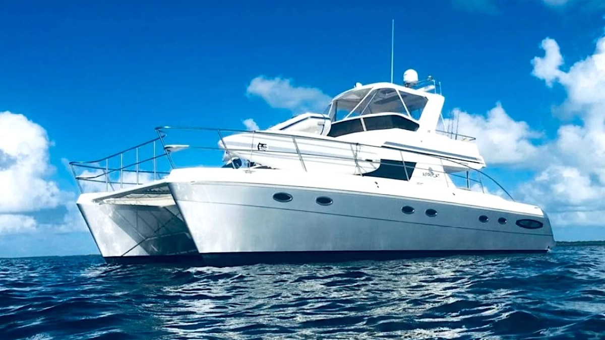 This 50 foot AfriCat Yacht Charter is shown underway on crystal blue Gulf of America waters near Fort Myers, featuring the sleek catamaran hull design and spacious flybridge against a bright Southwest Florida sky.