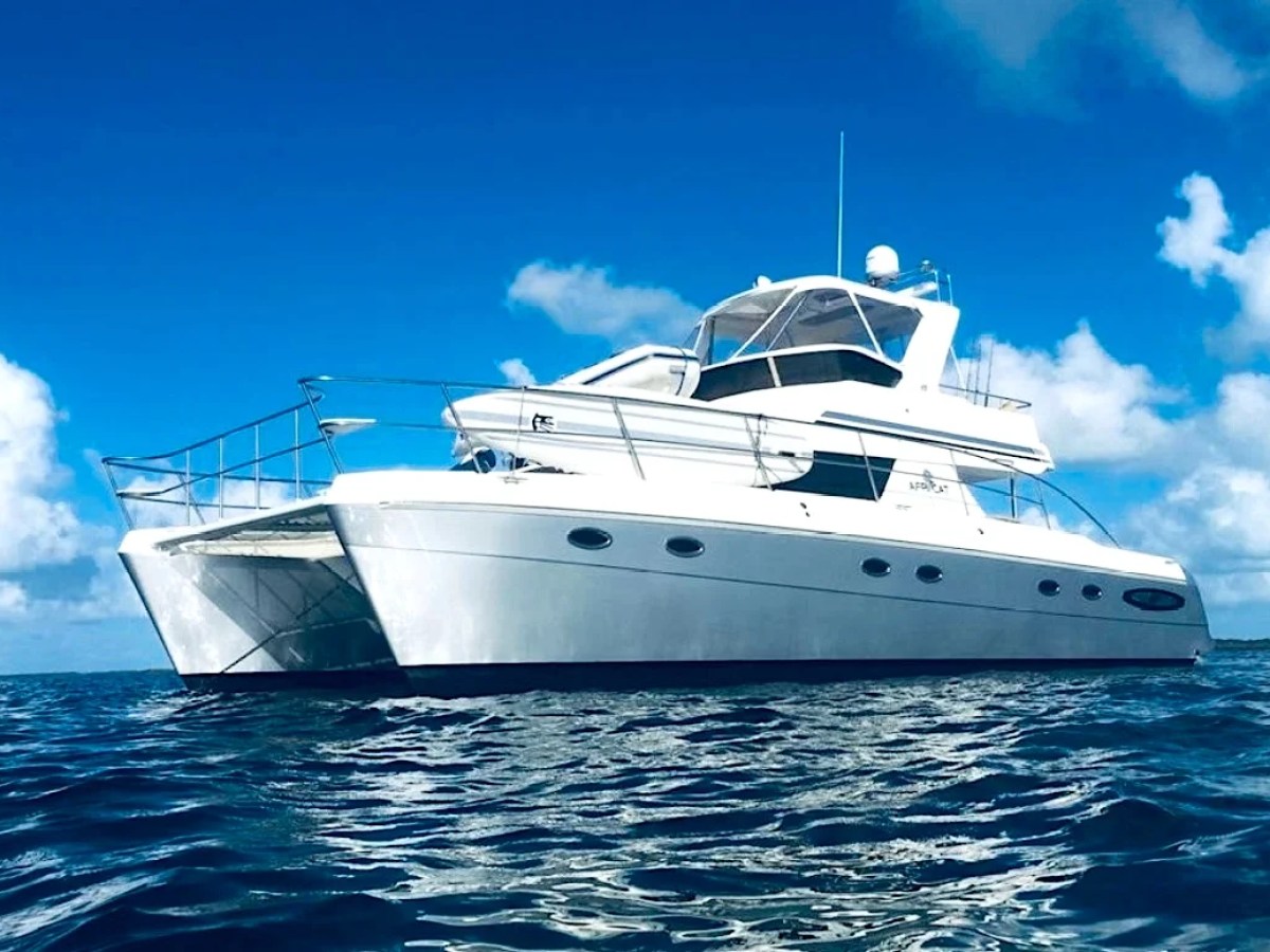 This 50 foot AfriCat Yacht Charter is shown underway on crystal blue Gulf of America waters near Fort Myers, featuring the sleek catamaran hull design and spacious flybridge against a bright Southwest Florida sky.